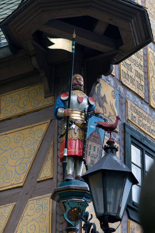 Hölzerne Ritterfigur an der Fassade, auf der Laterne die namenspendende »Rothe Amsel«